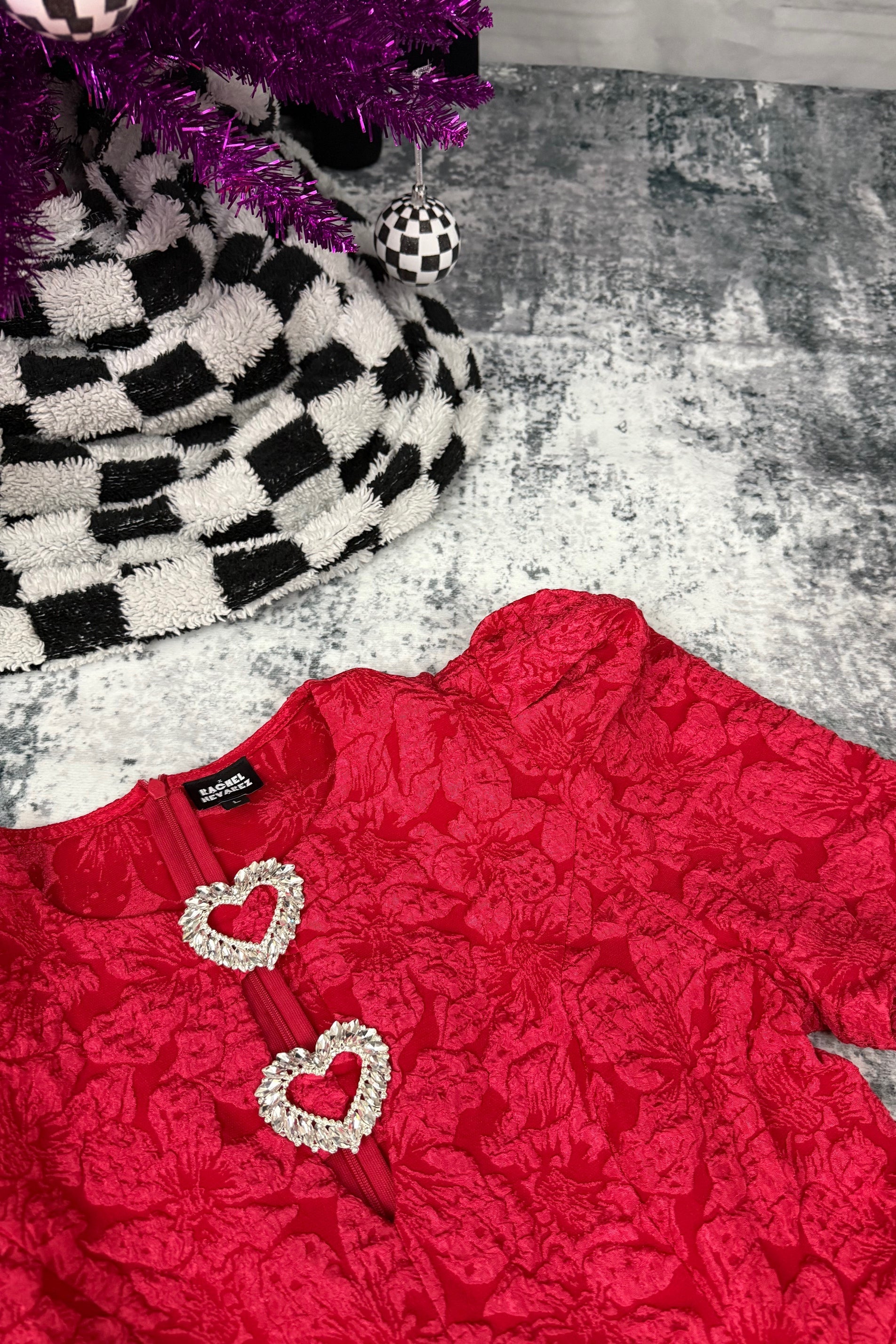 Red lace bodysuit with heart-shaped embellishments on a textured surface