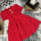 Red textured dress on a gray textured surface with decorative items around