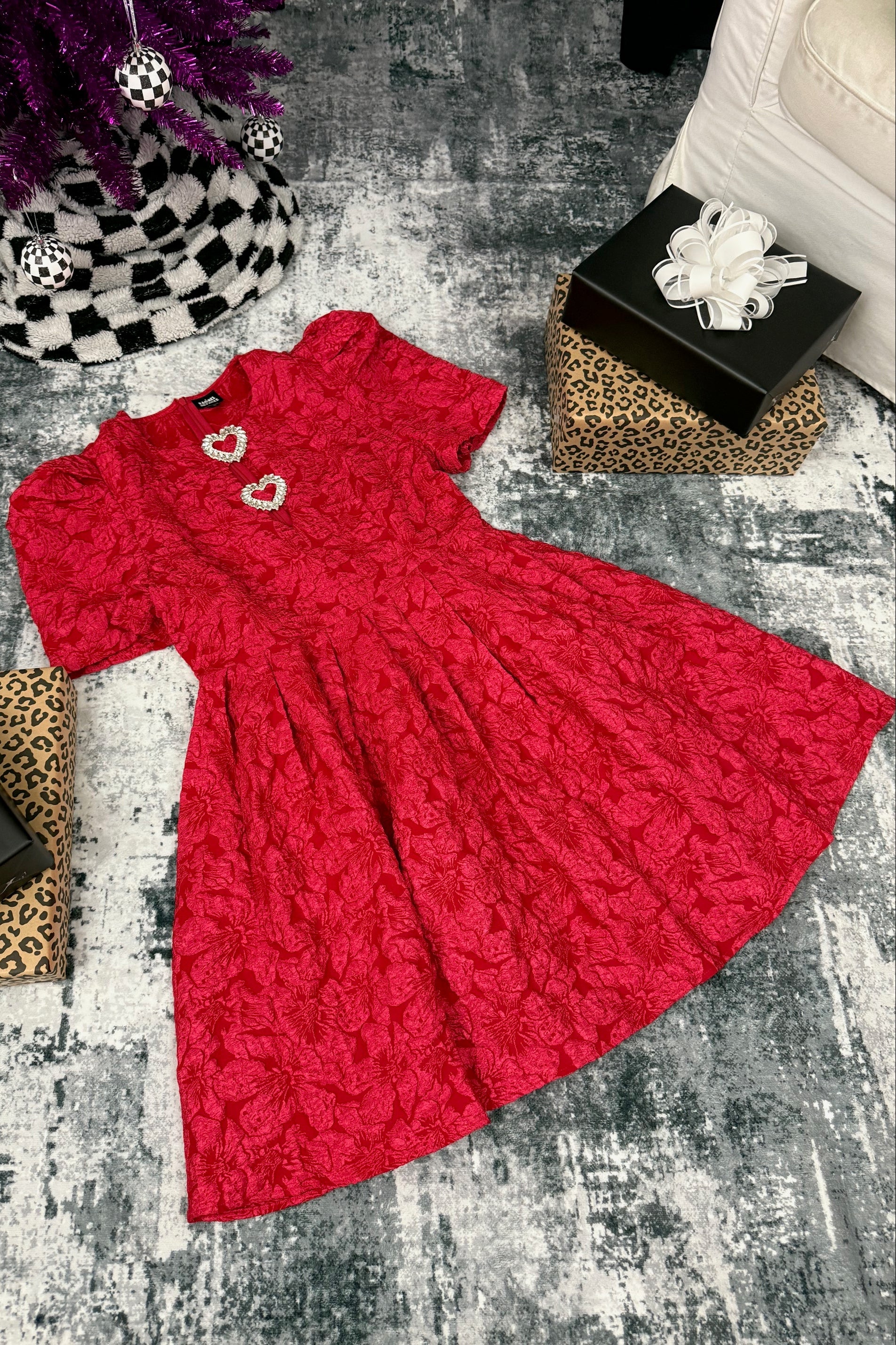 Red textured dress on a gray textured surface with decorative items around