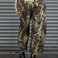 Person wearing leopard print pants and black boots in front of a metallic shutter.