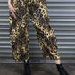 Person wearing leopard print pants and black boots standing in front of a metal shutter.