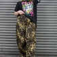 Person wearing a graphic t-shirt and leopard print pants standing in front of a metal shutter.
