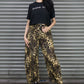 Woman wearing a black t-shirt and leopard print pants standing in front of a metallic shutter.