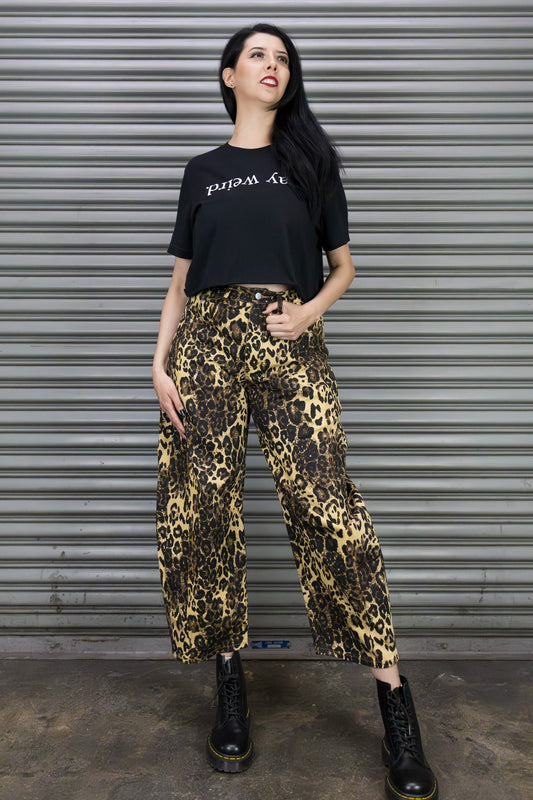 Woman wearing a black t-shirt and leopard print pants standing in front of a metallic shutter.