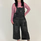 Person wearing black overalls and a red checkered shirt on a white background