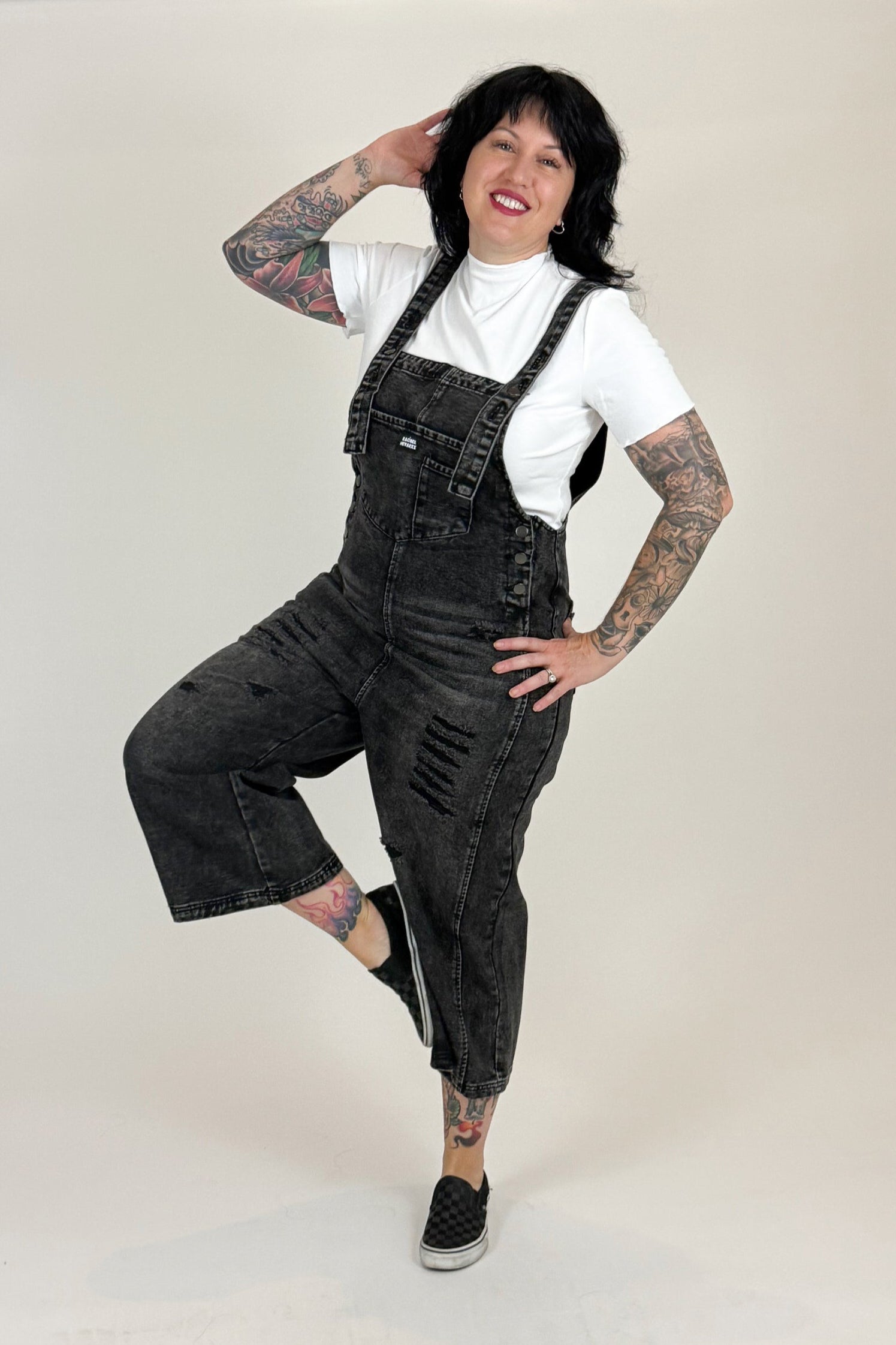 Woman wearing black overalls and a white shirt on a white background
