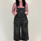 woman wearing black overalls and a pink checkered shirt on a white background