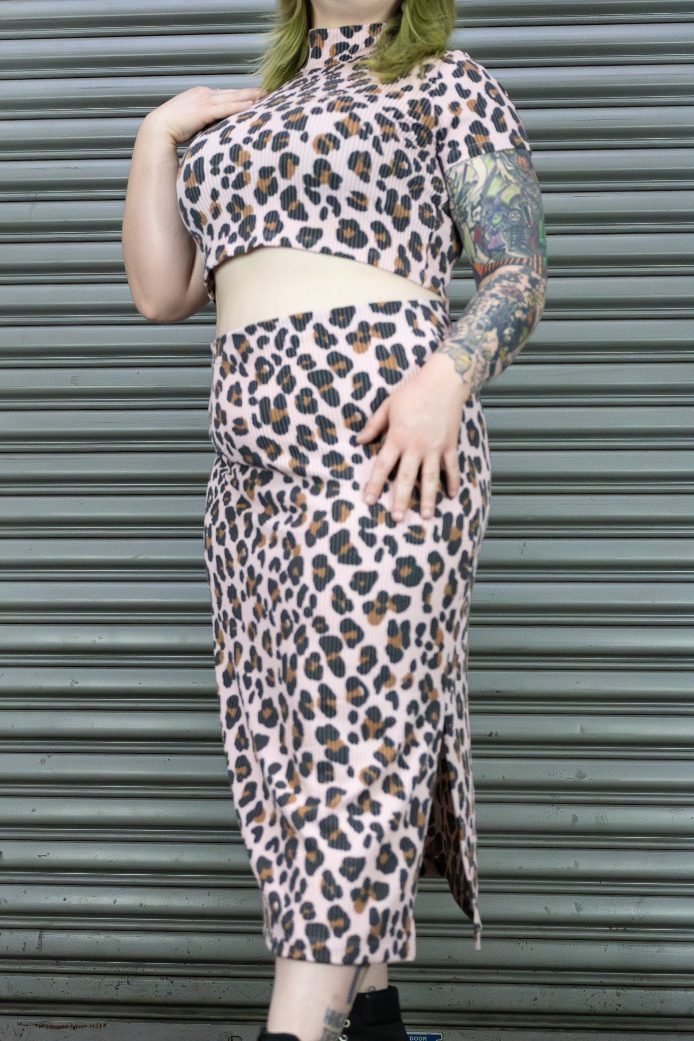 Person wearing a leopard print outfit in front of a metallic shutter.
