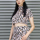 Woman wearing a leopard print outfit standing in front of a metal shutter.