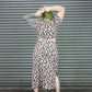 Person wearing a leopard print outfit in front of a corrugated metal wall.