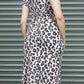 Person wearing a leopard 2 piece top and high-waist skirt standing in front of a metallic shutter.