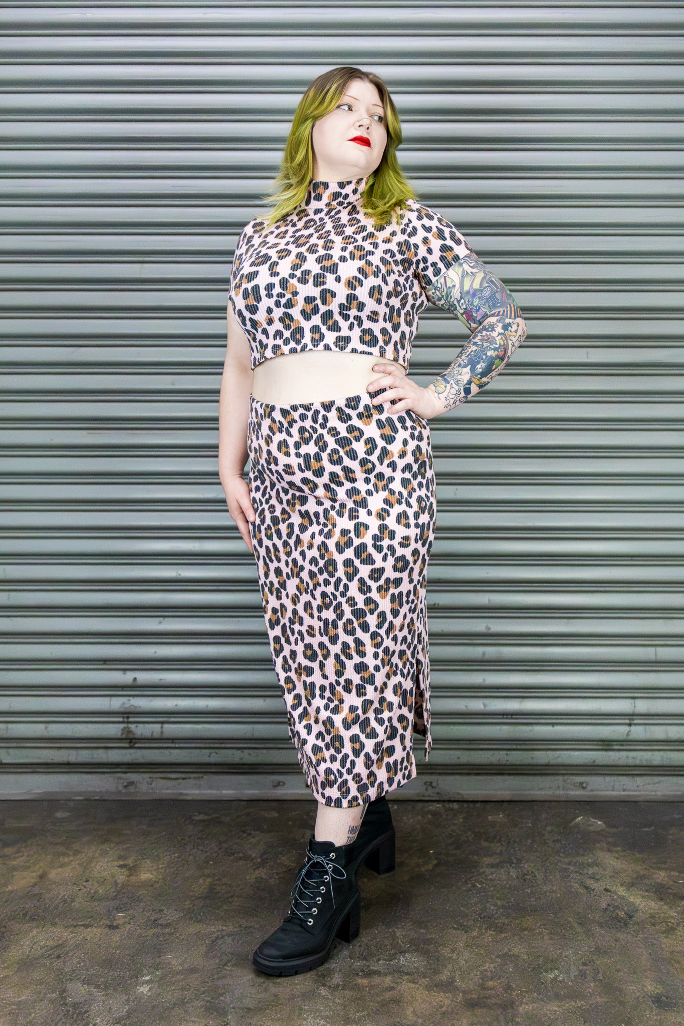 Person wearing a leopard print outfit standing against a metal shutter.