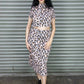 Woman wearing a leopard print outfit standing in front of a metal shutter.