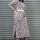 Person wearing a leopard print outfit standing in front of a metal shutter.
