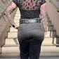 Person wearing a sheer leopard print top and black jeans on a staircase.