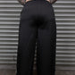Person wearing black wide-leg pants standing in front of a metallic shutter.