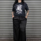 Person wearing a black graphic t-shirt and black pants standing in front of a metal shutter.