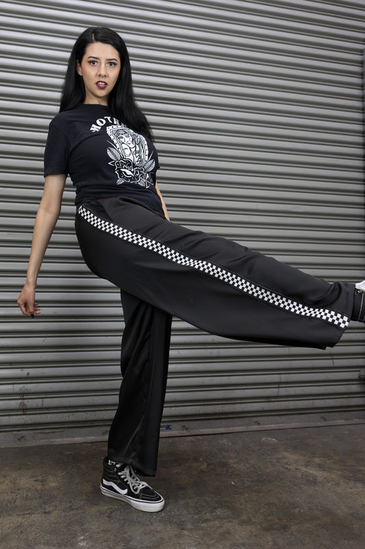 Person wearing a black outfit with checkered stripe in front of a metallic shutter.