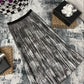 Black and white patterned scarf on a textured surface with decorative items.