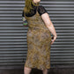 Woman wearing a patterned dress standing in front of a metallic shutter.