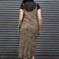 Person wearing a leopard print dress over a black top with sheer details, standing against a metallic shutter.