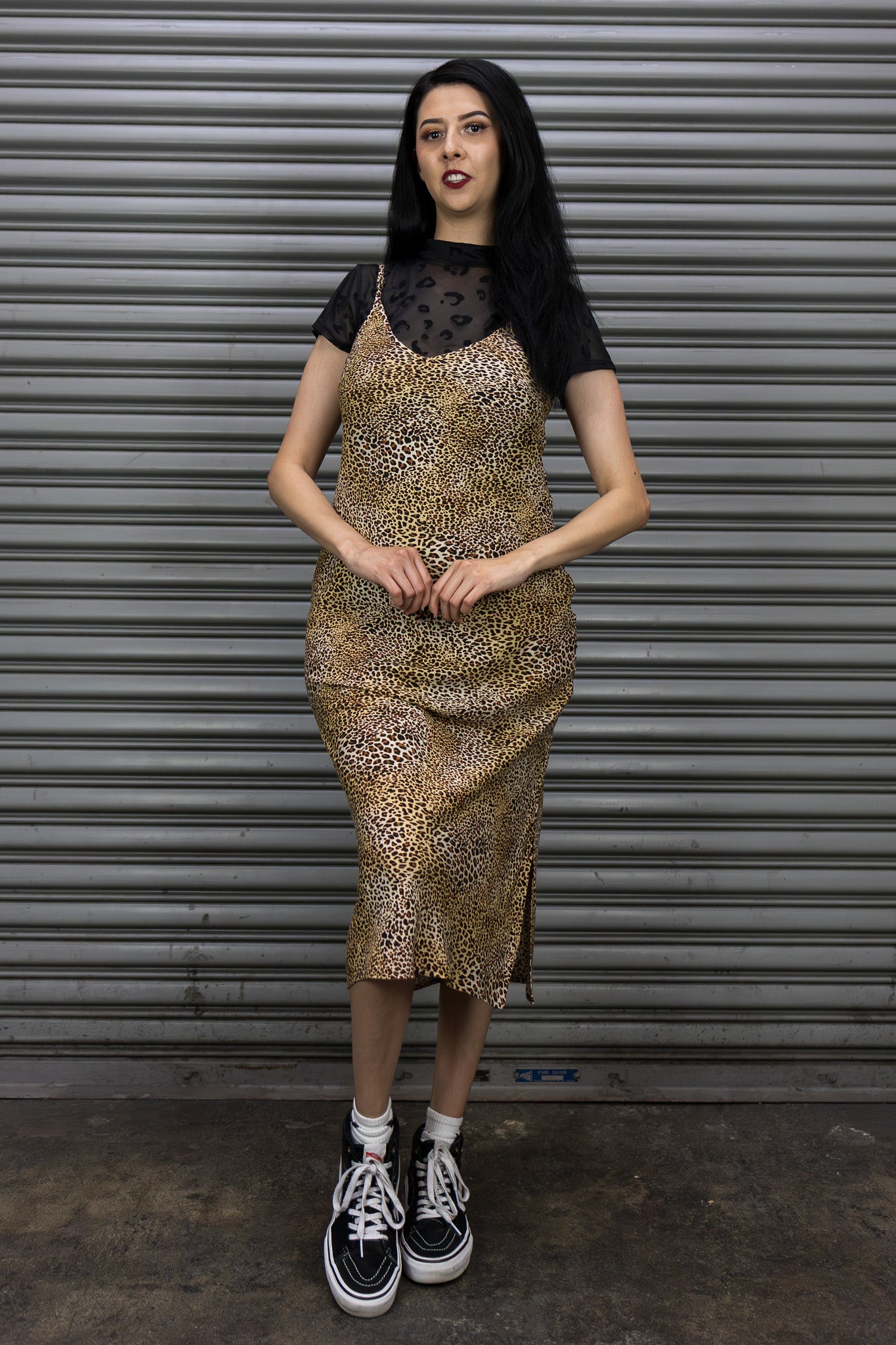 Woman wearing a leopard print dress with a black top against a metal shutter background