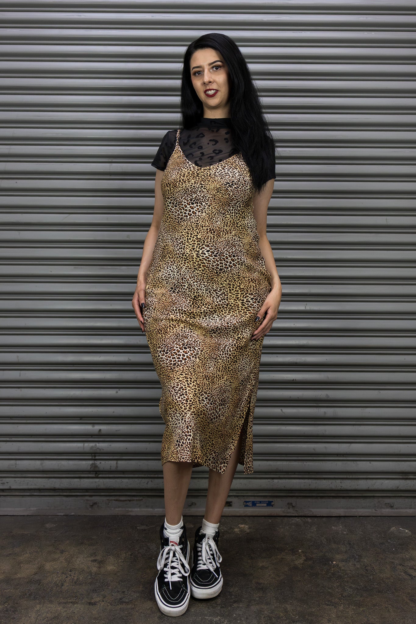 Woman wearing a leopard print dress with a black top against a metal shutter background