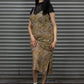 Woman wearing a patterned dress and black sneakers standing in front of a metal shutter.