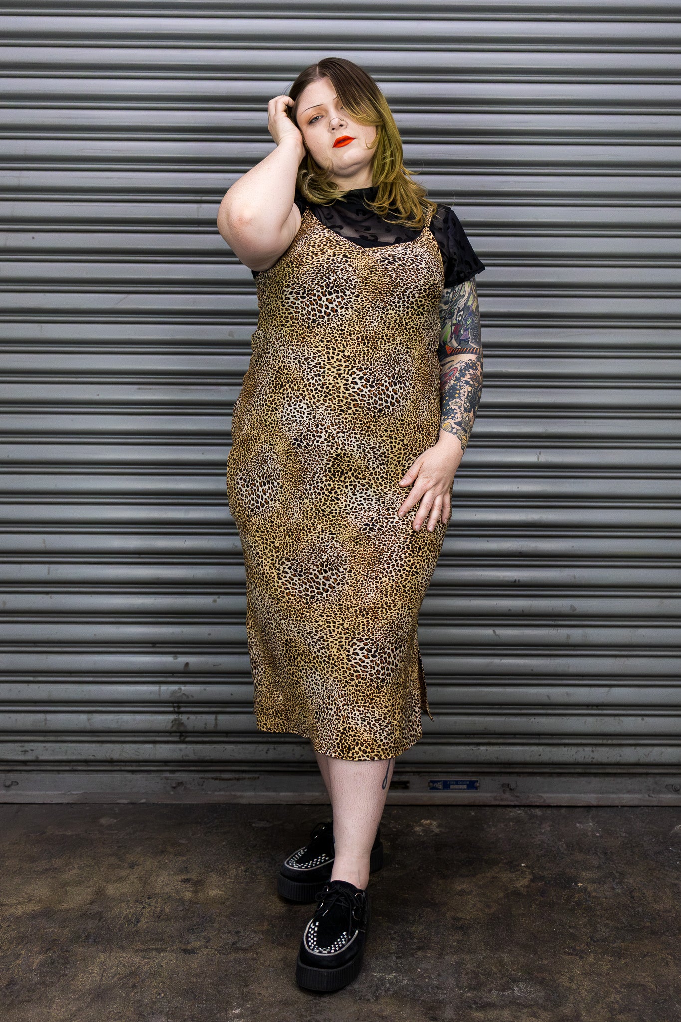 Person wearing a leopard print dress in front of a metal shutter.