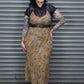 Person wearing a patterned dress with tattoos standing in front of a metal shutter.