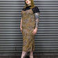 Person wearing a patterned dress with black accents against a metal shutter background