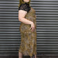 Person wearing a leopard print dress with black platform shoes in front of a metal shutter.