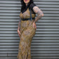 Woman in a leopard print dress standing against a metal shutter.