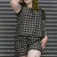 Person wearing a plaid outfit standing in front of a metallic shutter.