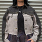 Person wearing a denim jacket and plaid pants standing in front of a metal shutter.