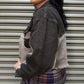 Woman wearing a denim jacket and plaid skirt standing against a metal shutter.