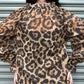 Person wearing a leopard print shirt with a plain background