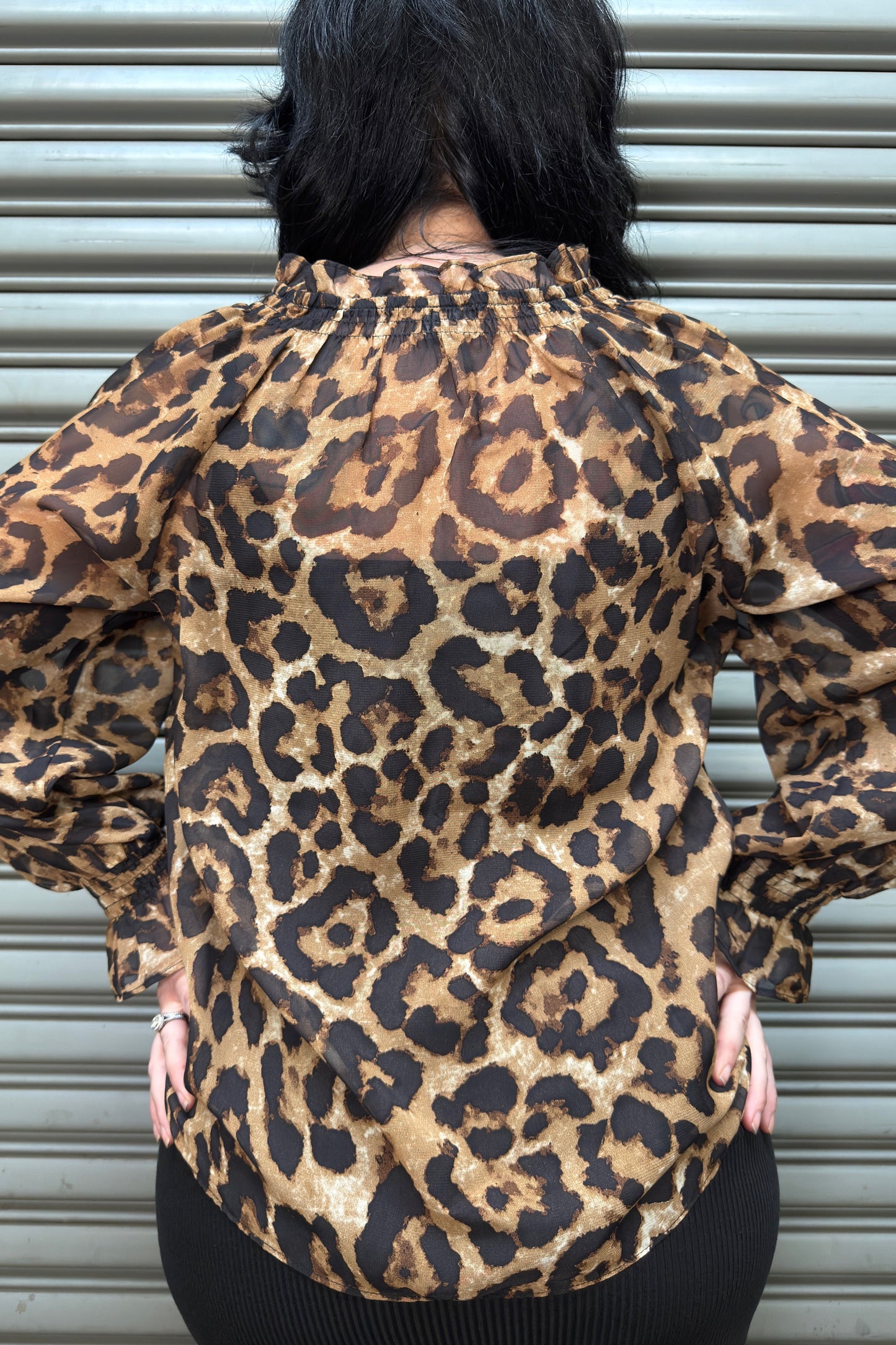 Person wearing a leopard print shirt with a plain background