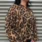 Woman wearing a leopard print blouse standing against a metallic shutter.