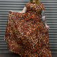 Person wearing a leopard print dress standing against a metallic shutter.
