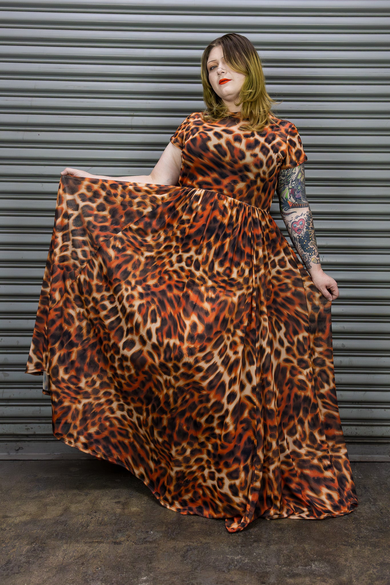 Person wearing a leopard print dress standing against a metallic shutter.