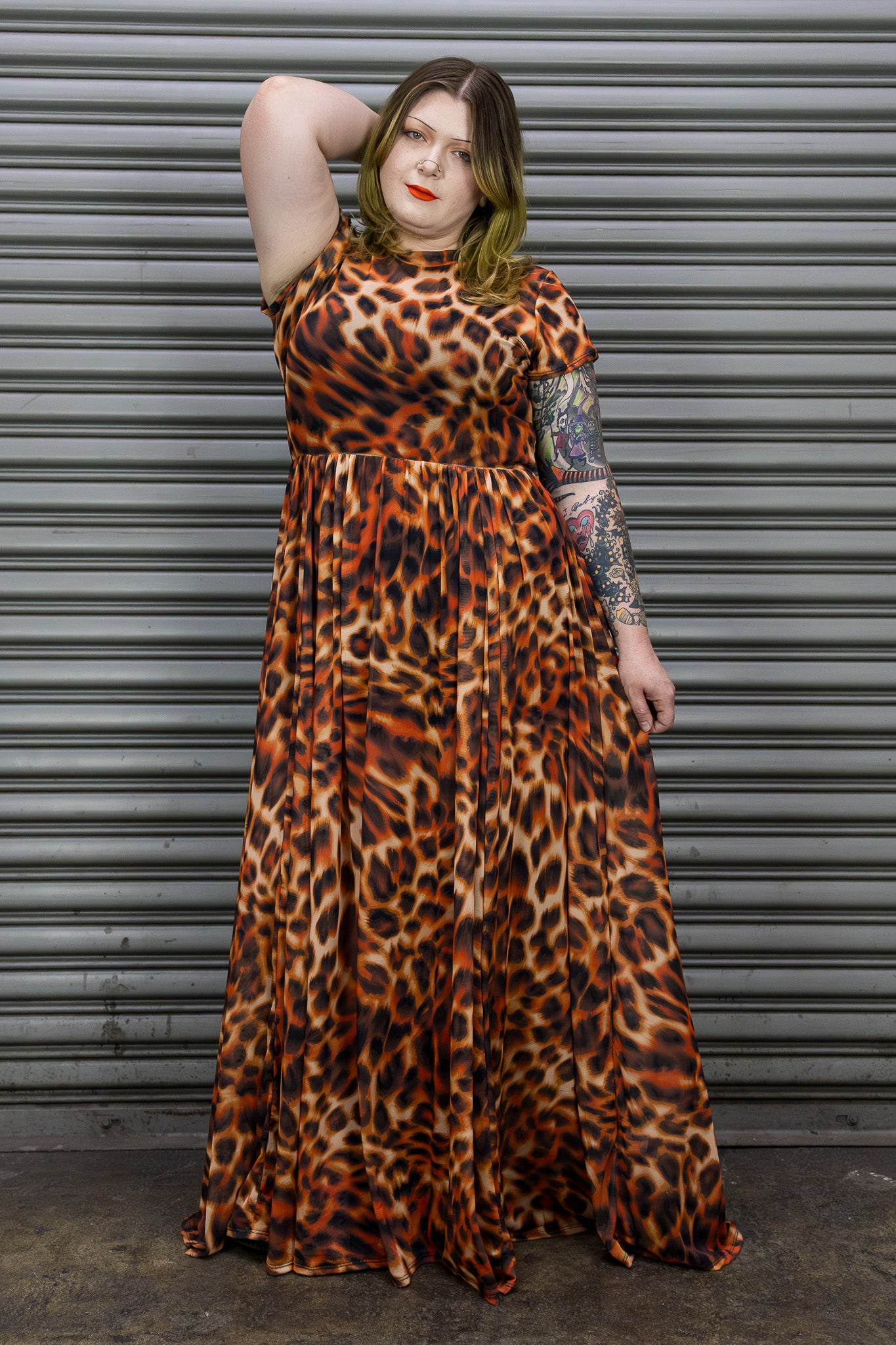 Person wearing a leopard print dress standing against a metallic shutter.