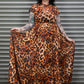 Person wearing a leopard print dress standing in front of a metal shutter.