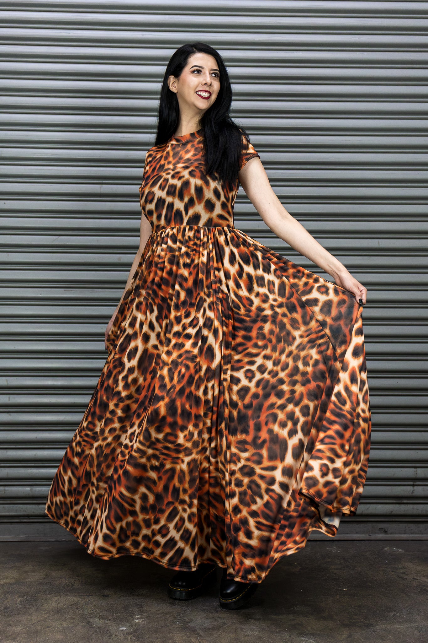 Woman wearing a leopard print dress standing against a metallic shutter.