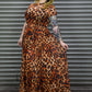 Person wearing a leopard print dress standing against a metallic shutter.