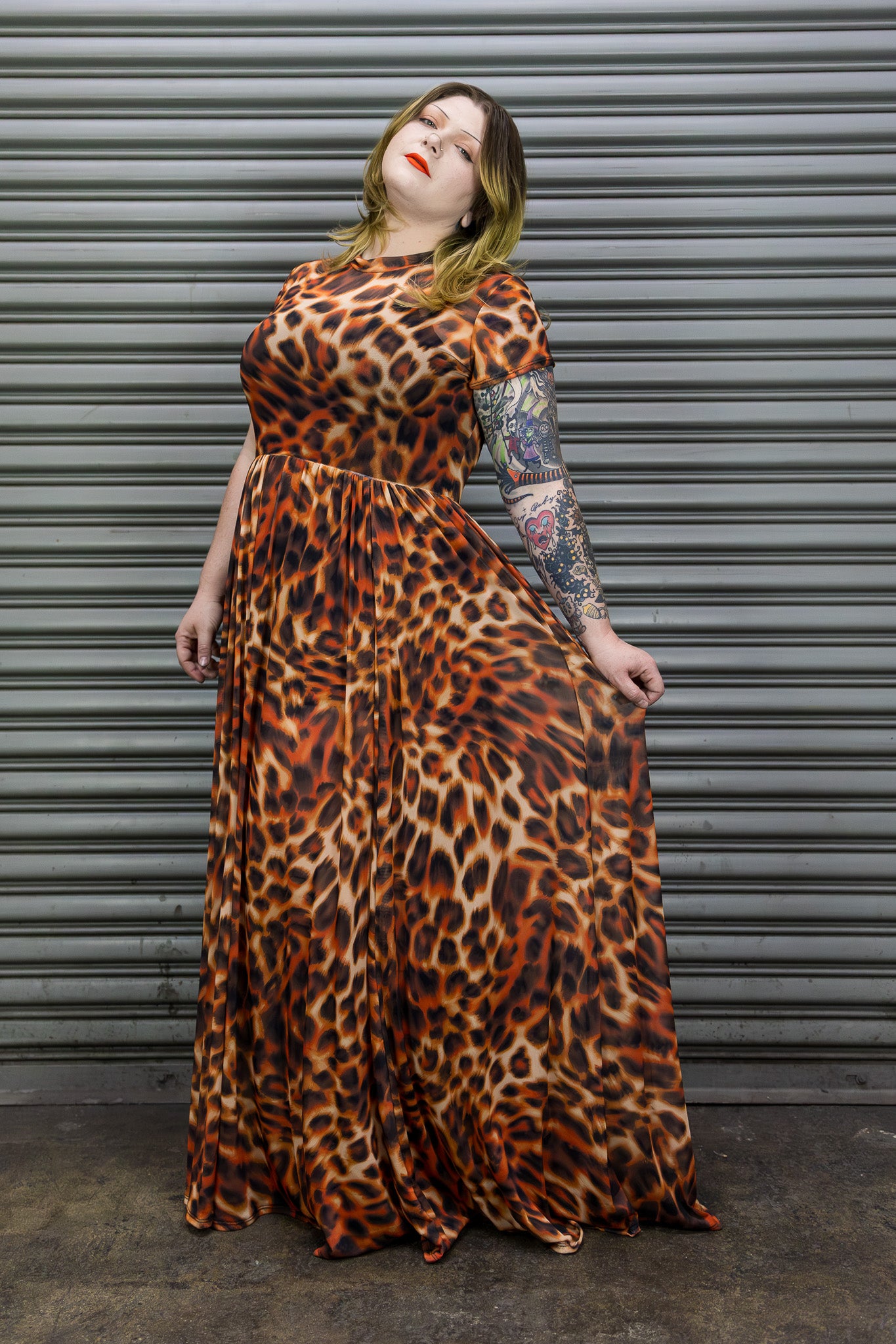 Person wearing a leopard print dress standing against a metallic shutter.