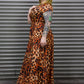 Person wearing a leopard print dress standing against a metallic background.