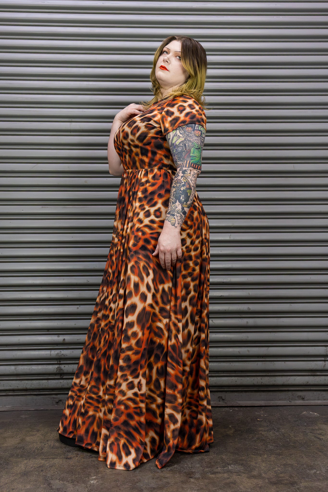 Person wearing a leopard print dress standing against a metallic background.