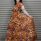 Woman wearing a leopard print dress standing in front of a metal shutter.