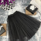 Black pleated skirt on a textured surface with decorative items around